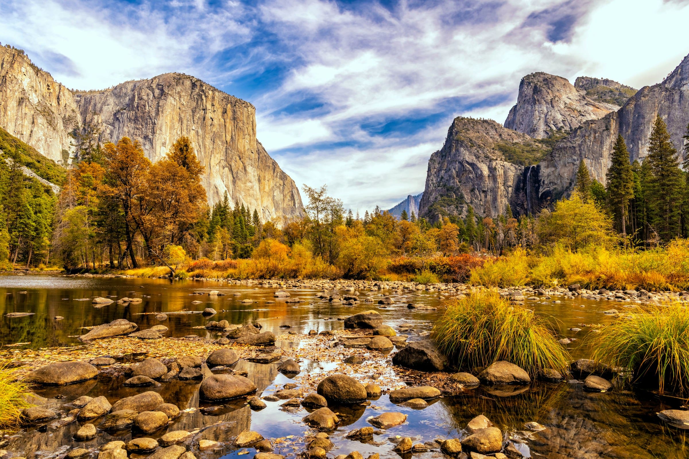 Yosemite Valley in herfst met El Capitan, gouden bomen en Merced River met rotsen in voorgrond