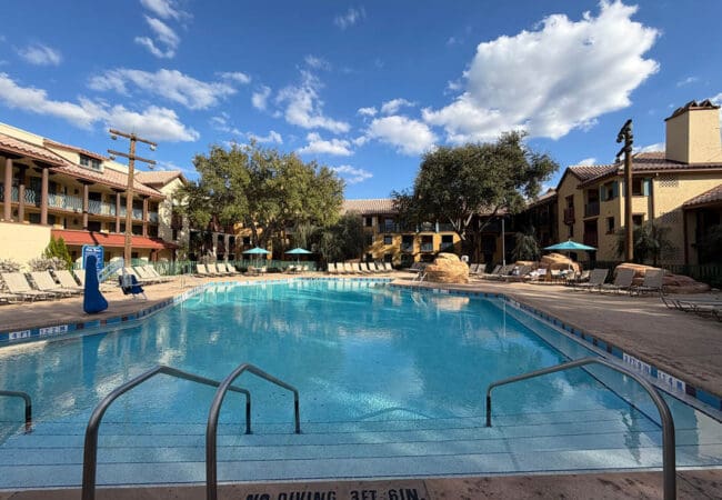 Zwembad bij Disney’s Coronado Springs Resort met ligbedden en Spaanse architectuur in de zon.