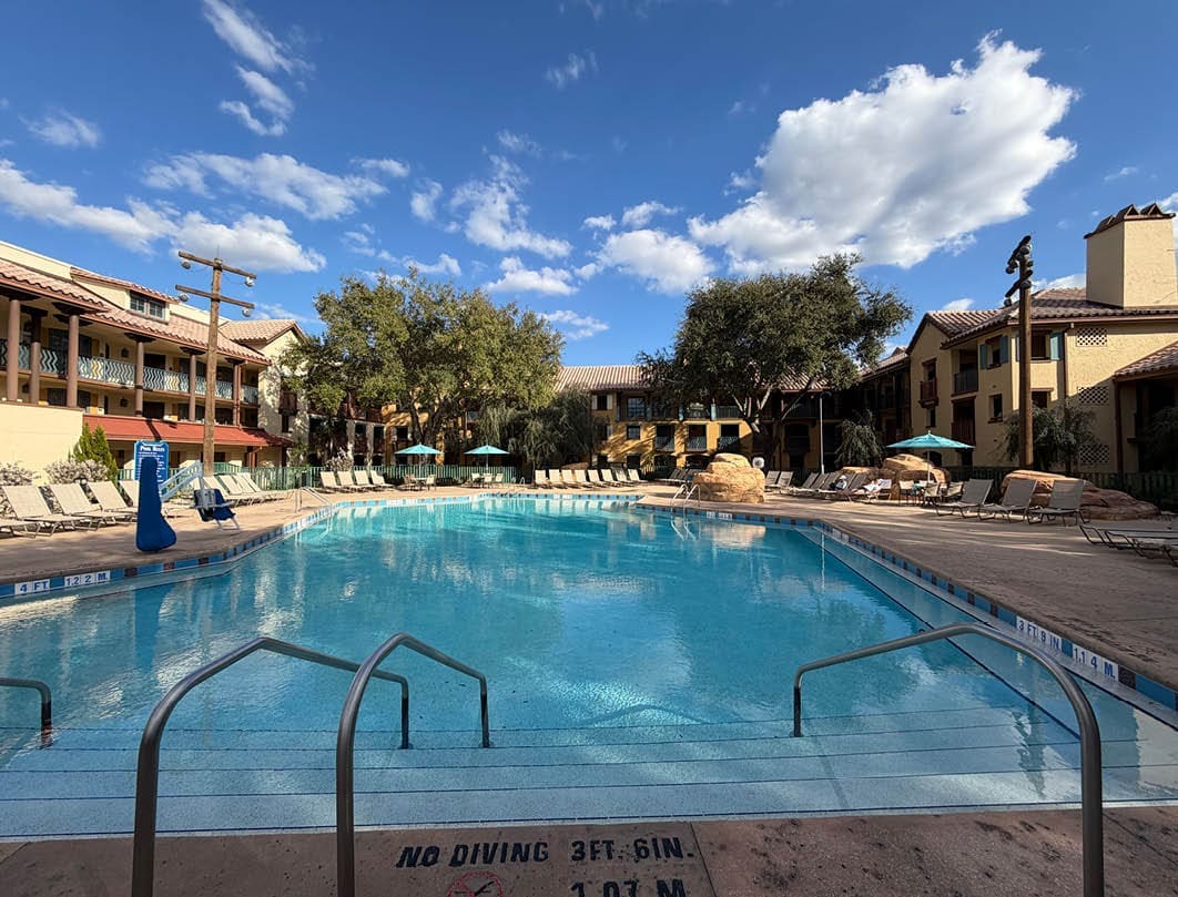 Zwembad bij Disney’s Coronado Springs Resort met ligbedden en Spaanse architectuur in de zon.