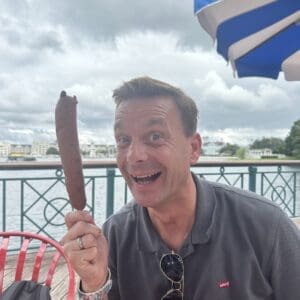 Ralf Verhoef houdt lachend een corn dog op een stokje omhoog bij Disney's BoardWalk