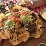 Enorme schaal loaded nachos met guacamole, pico de gallo, kaas en pulled beef en chicken